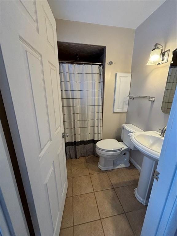 bathroom featuring toilet, sink, tile patterned floors, and walk in shower