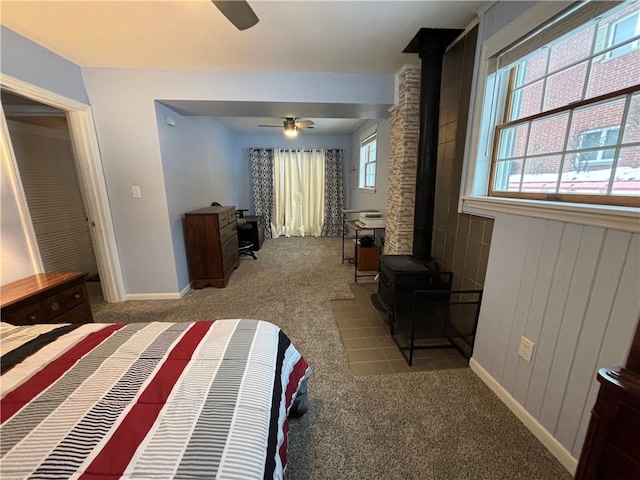 carpeted bedroom with ceiling fan and a wood stove