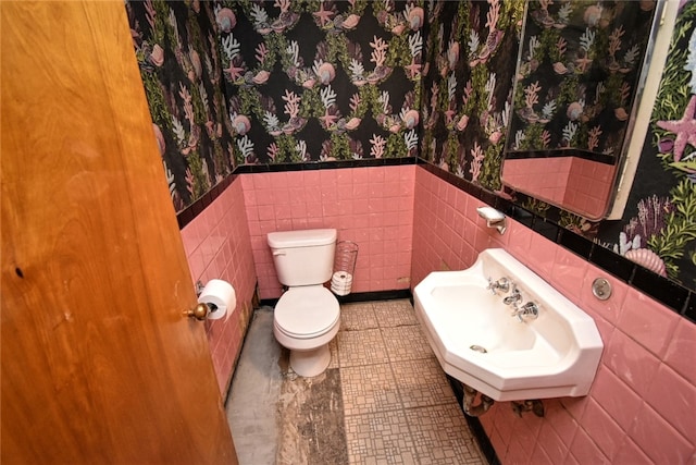 bathroom with toilet, tile walls, and sink