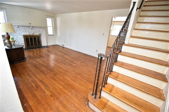 unfurnished living room featuring wood-type flooring and a stone fireplace