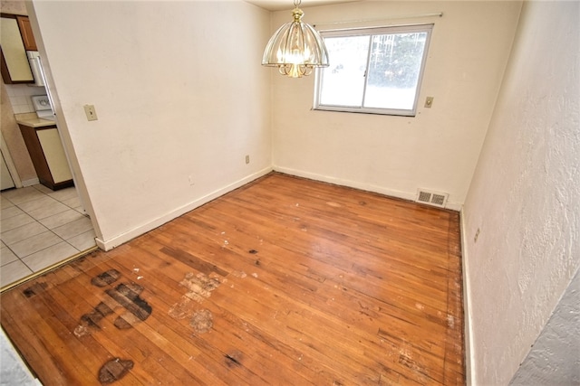 spare room featuring light tile patterned floors and a notable chandelier