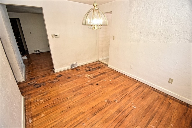 unfurnished dining area with dark wood-type flooring and a notable chandelier