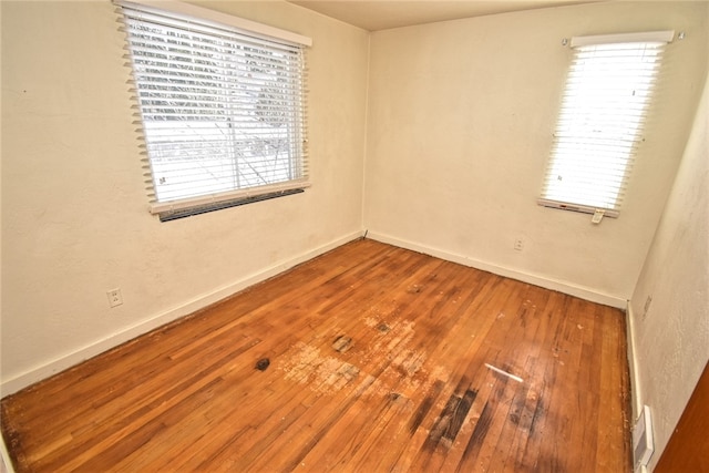 empty room with plenty of natural light and hardwood / wood-style flooring