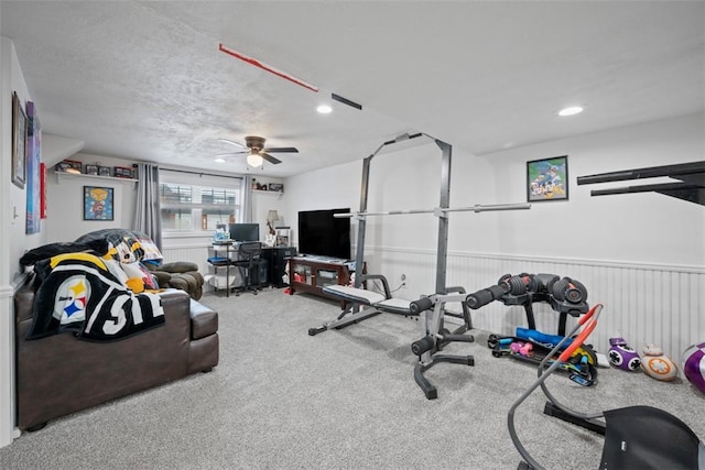 exercise area featuring ceiling fan, a textured ceiling, and carpet flooring