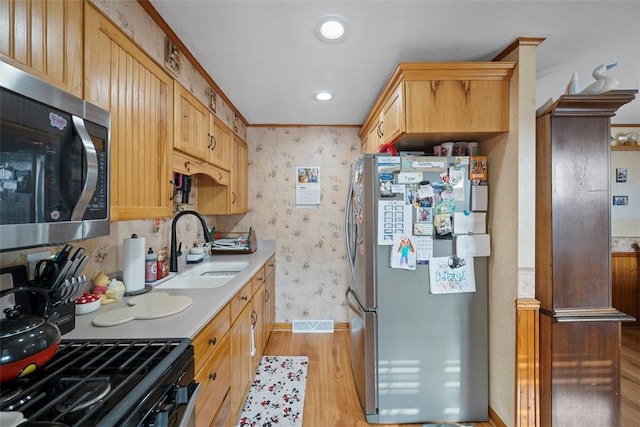 kitchen with light brown cabinetry, sink, stainless steel appliances, and light wood-type flooring