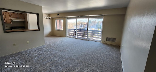 empty room with light colored carpet and a chandelier