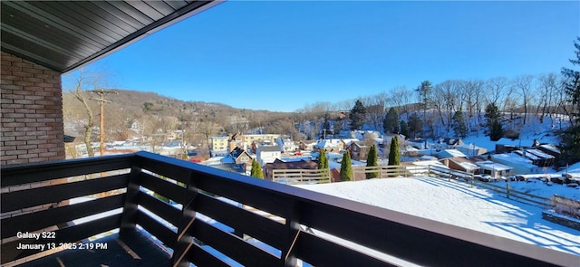 snow covered back of property featuring a mountain view