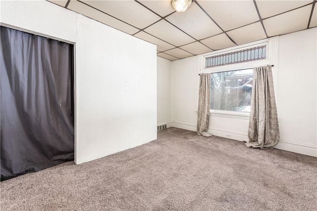 spare room with a paneled ceiling and carpet