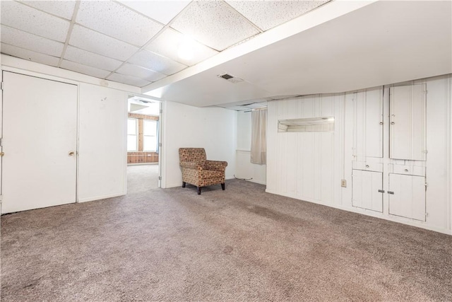 basement with a paneled ceiling and carpet