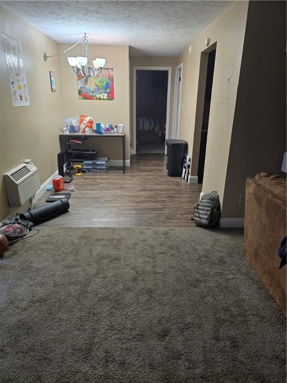 recreation room featuring carpet floors, a textured ceiling, a wall unit AC, and a chandelier