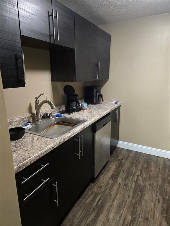 kitchen featuring stainless steel dishwasher, dark hardwood / wood-style flooring, sink, and a textured ceiling