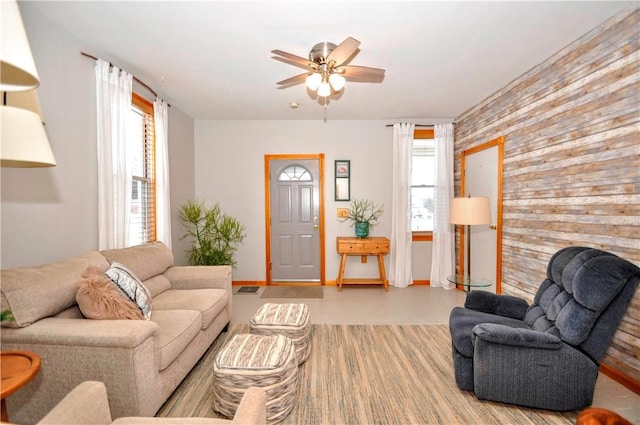 living room featuring ceiling fan, a wealth of natural light, and wooden walls