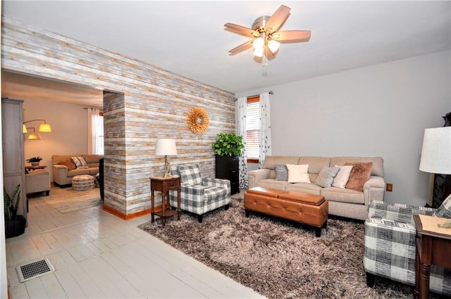 living room with ceiling fan and wood walls