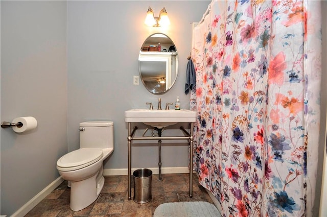 bathroom featuring toilet, sink, and a shower with shower curtain