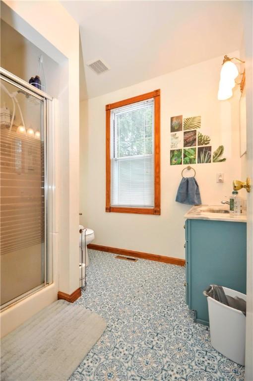 bathroom with an enclosed shower, vanity, and toilet