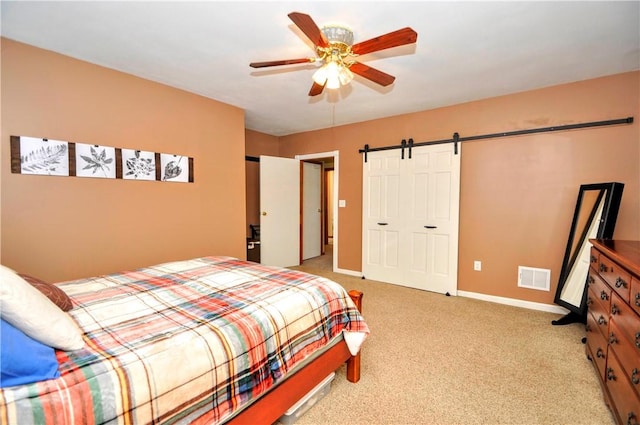 carpeted bedroom with ceiling fan, a closet, and a barn door