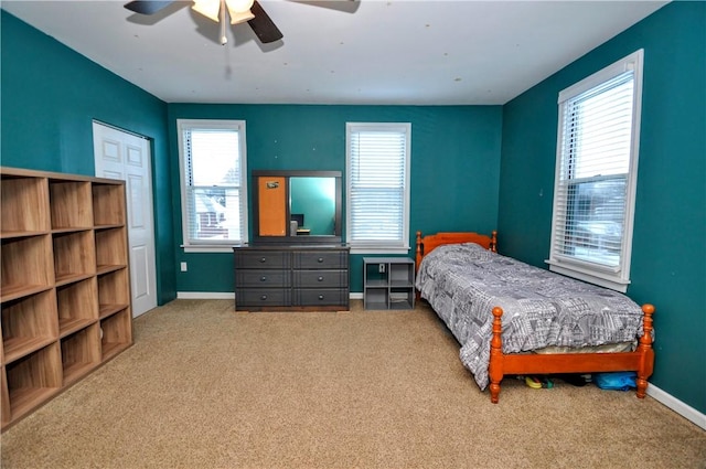 bedroom featuring ceiling fan, light colored carpet, and multiple windows