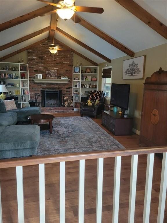 living room featuring lofted ceiling with beams, a brick fireplace, hardwood / wood-style flooring, and ceiling fan