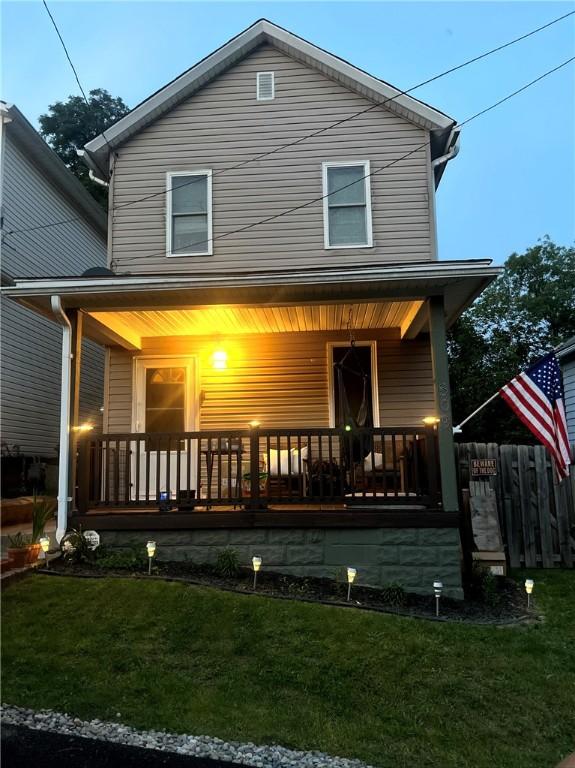 back of property featuring covered porch and a yard