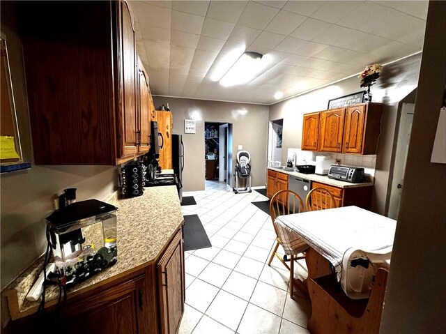 kitchen with appliances with stainless steel finishes, tasteful backsplash, sink, light tile patterned floors, and light stone countertops