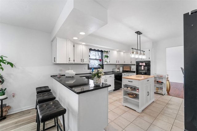 kitchen with light tile patterned floors, white cabinetry, kitchen peninsula, hanging light fixtures, and black appliances