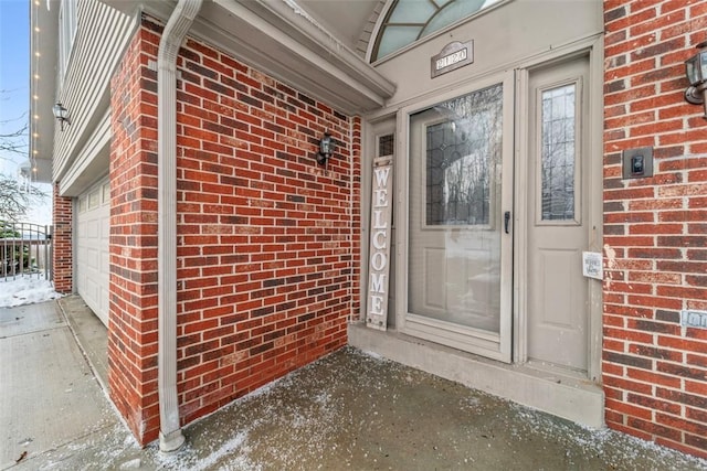 snow covered property entrance with a garage