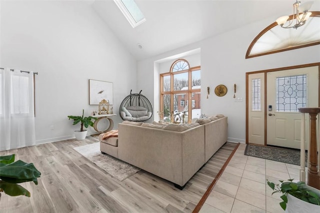 living room with high vaulted ceiling, light hardwood / wood-style floors, and a skylight