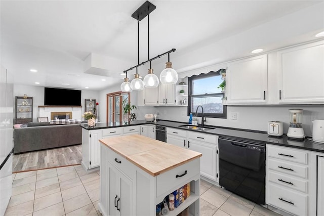 kitchen featuring decorative light fixtures, a kitchen island, sink, black dishwasher, and white cabinets