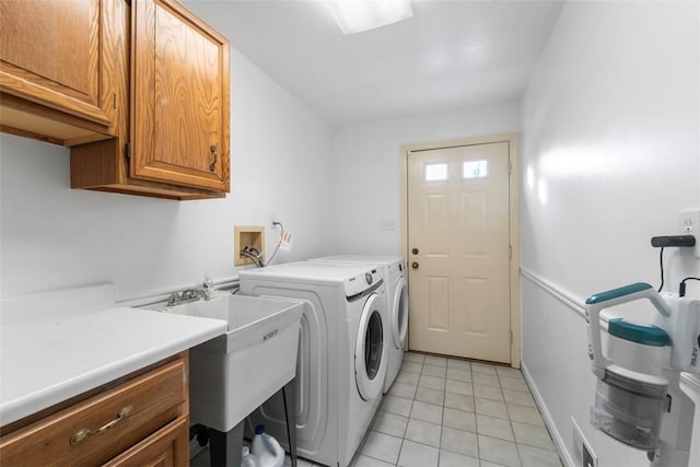 clothes washing area featuring washing machine and dryer, cabinets, and light tile patterned flooring