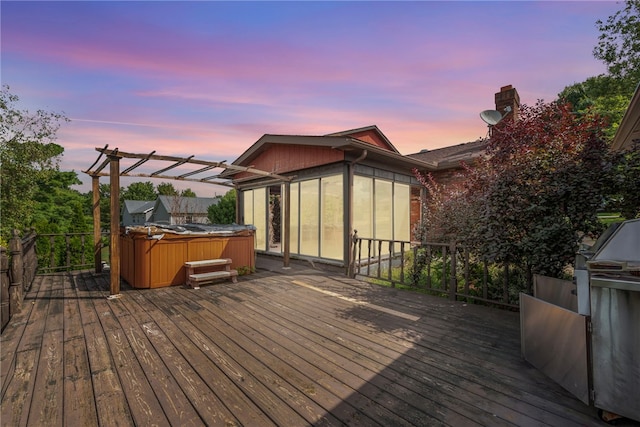 deck at dusk featuring a pergola and a hot tub