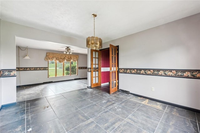 spare room featuring ceiling fan with notable chandelier and french doors