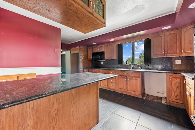 kitchen featuring sink, tasteful backsplash, dark stone counters, and light tile patterned flooring