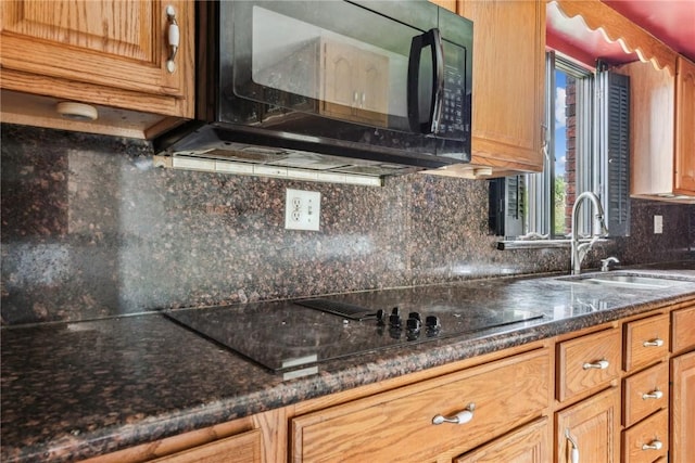 kitchen featuring decorative backsplash, sink, black appliances, and dark stone countertops