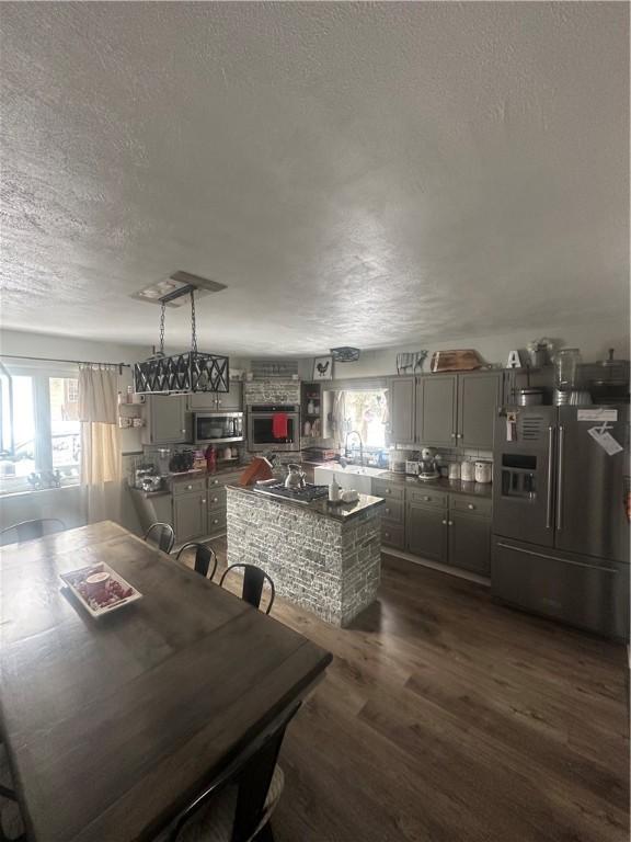 kitchen with sink, dark wood-type flooring, appliances with stainless steel finishes, gray cabinetry, and a textured ceiling