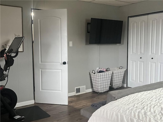 bedroom with a closet, dark hardwood / wood-style flooring, and a drop ceiling