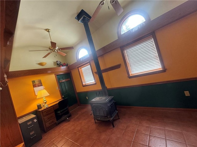 interior space featuring ceiling fan, tile patterned floors, and a wood stove