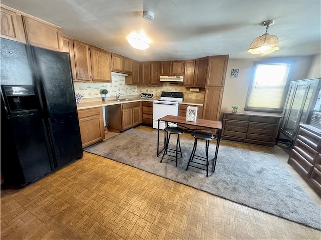 kitchen featuring white range with electric stovetop, black fridge, light parquet flooring, pendant lighting, and sink