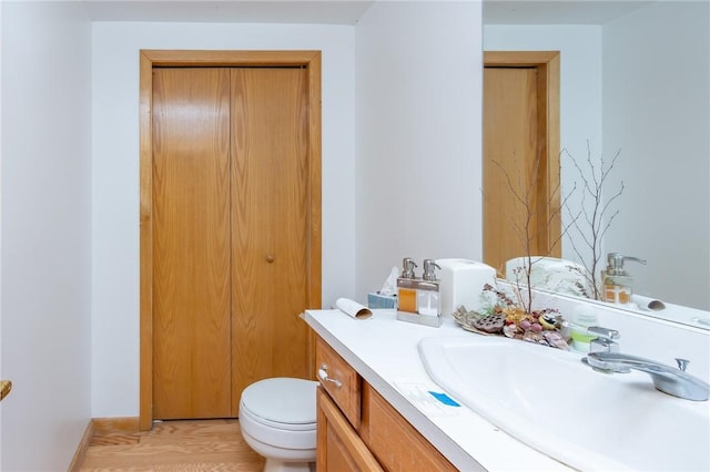 bathroom with toilet, vanity, and hardwood / wood-style floors