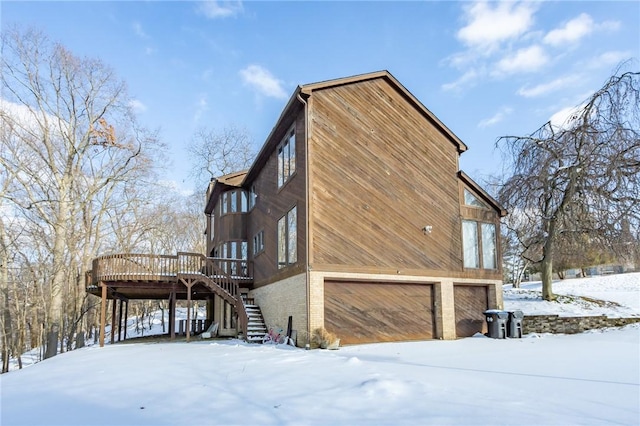 view of snowy exterior with a garage and a deck