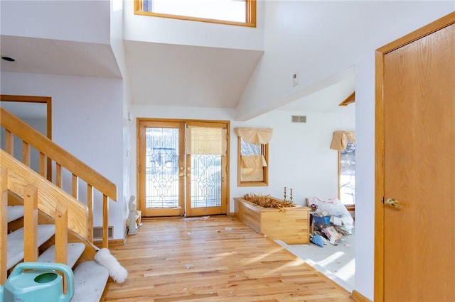 foyer with light wood-type flooring, french doors, and high vaulted ceiling