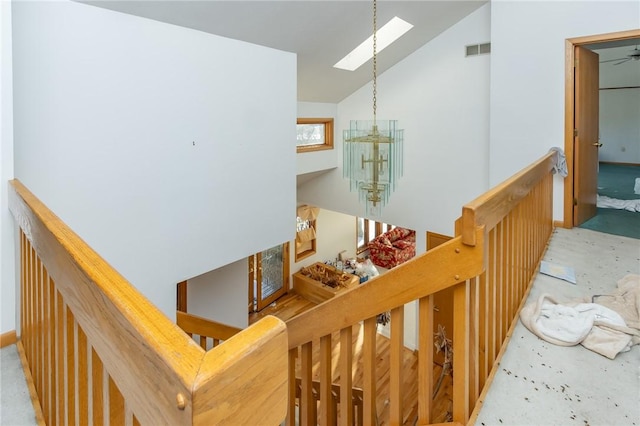 stairway featuring vaulted ceiling with skylight and an inviting chandelier