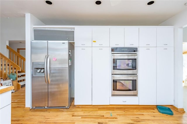 kitchen with light hardwood / wood-style flooring, stainless steel appliances, and white cabinetry