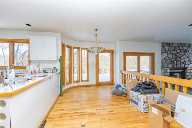 kitchen with decorative light fixtures, white cabinets, a healthy amount of sunlight, and a fireplace