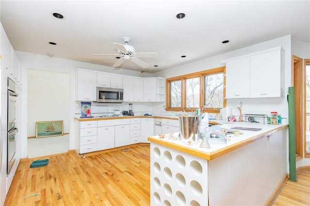 kitchen featuring light wood-type flooring, stainless steel appliances, white cabinets, and kitchen peninsula