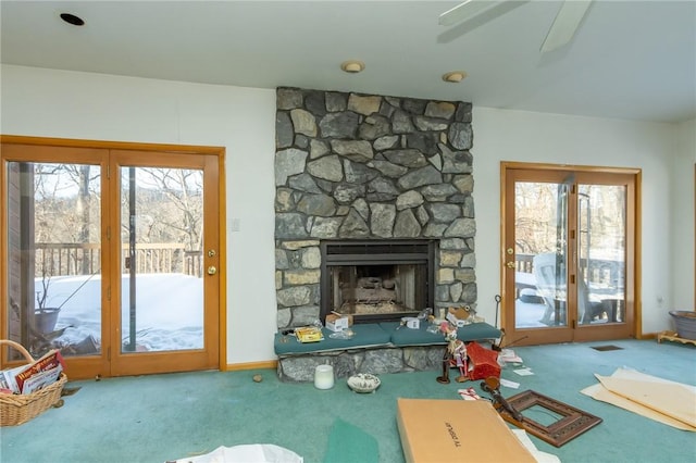 carpeted living room featuring ceiling fan, a healthy amount of sunlight, and a stone fireplace