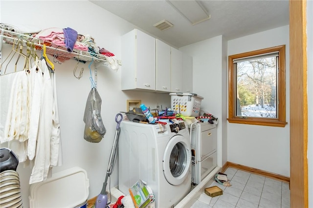 washroom featuring washer and dryer, cabinets, and light tile patterned floors