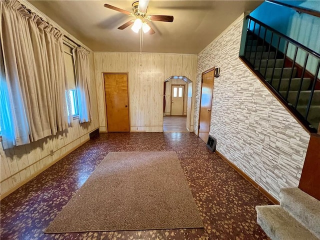 spare room featuring ceiling fan, plenty of natural light, and wooden walls