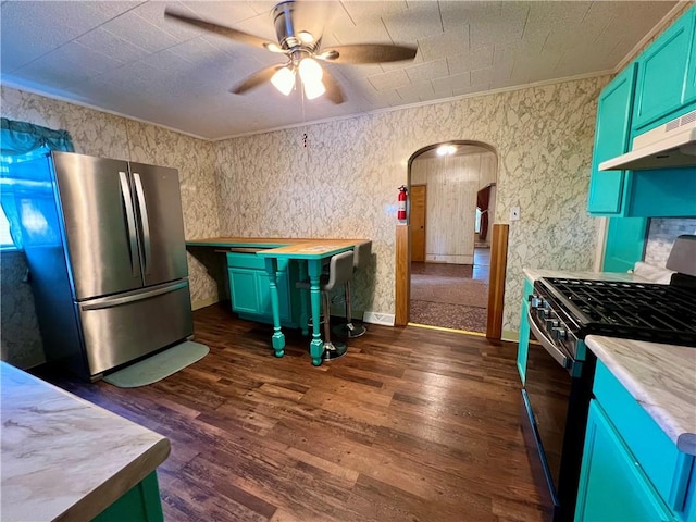 kitchen with ceiling fan, black gas range, dark wood-type flooring, ornamental molding, and stainless steel fridge