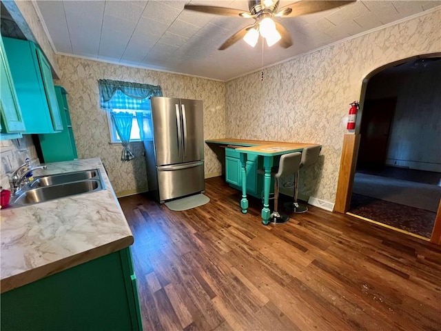 kitchen featuring ceiling fan, sink, dark hardwood / wood-style flooring, ornamental molding, and stainless steel fridge