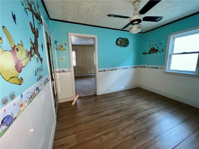 unfurnished room featuring ceiling fan, a baseboard heating unit, dark hardwood / wood-style flooring, and ornamental molding